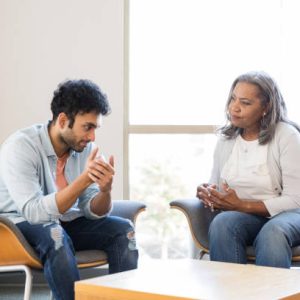 The young adult male gestures while speaking to his mental health therapist about a triggered experience he had yesterday at work.